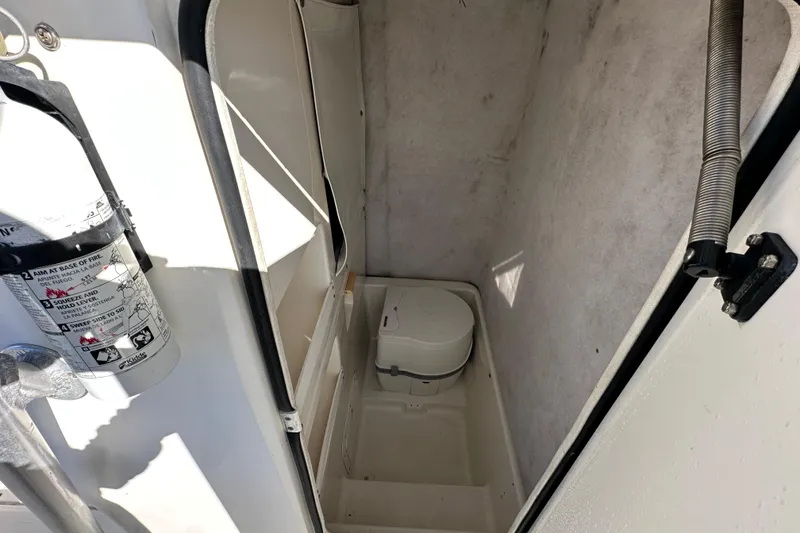 Slide: The Image of 1999 Robalo 2420 Center Console boat interior with fire extinguisher and portable toilet. - 30