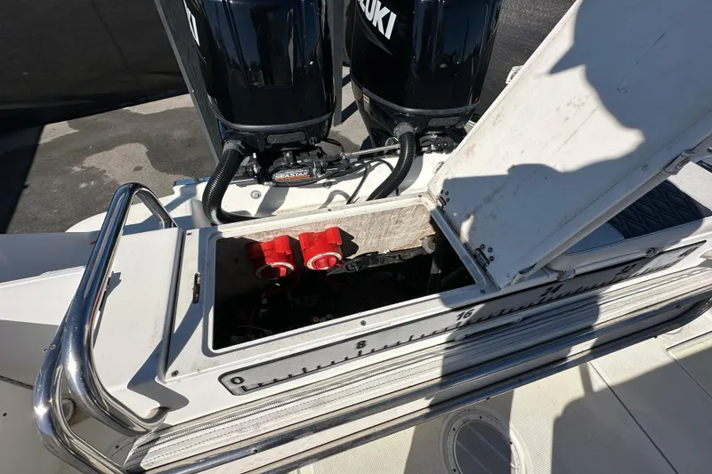 Slide: The Image of 1999 Robalo 2420 Center Console boat with open hatch and dual Suzuki engines. - 49