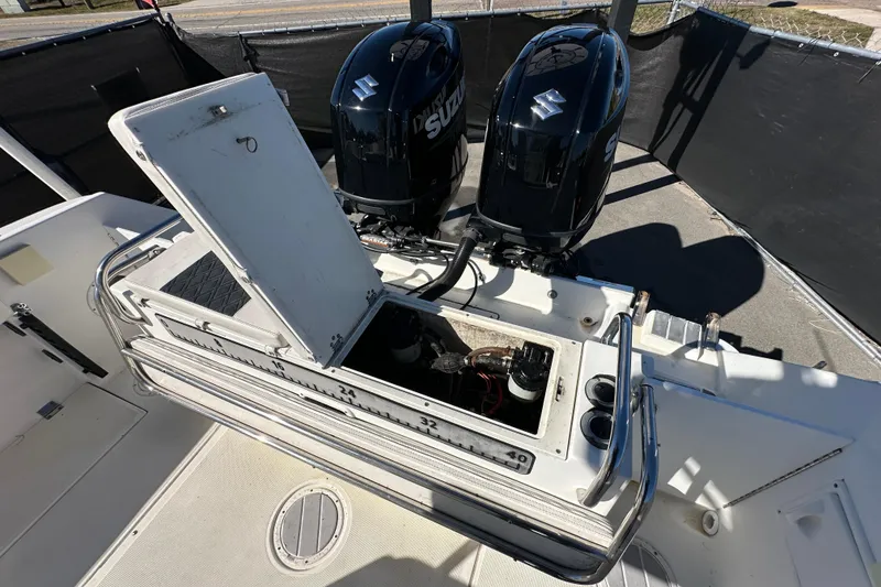 Slide: The Image of 1999 Robalo 2420 Center Console boat with open storage compartment and dual Suzuki outboard engines. - 52