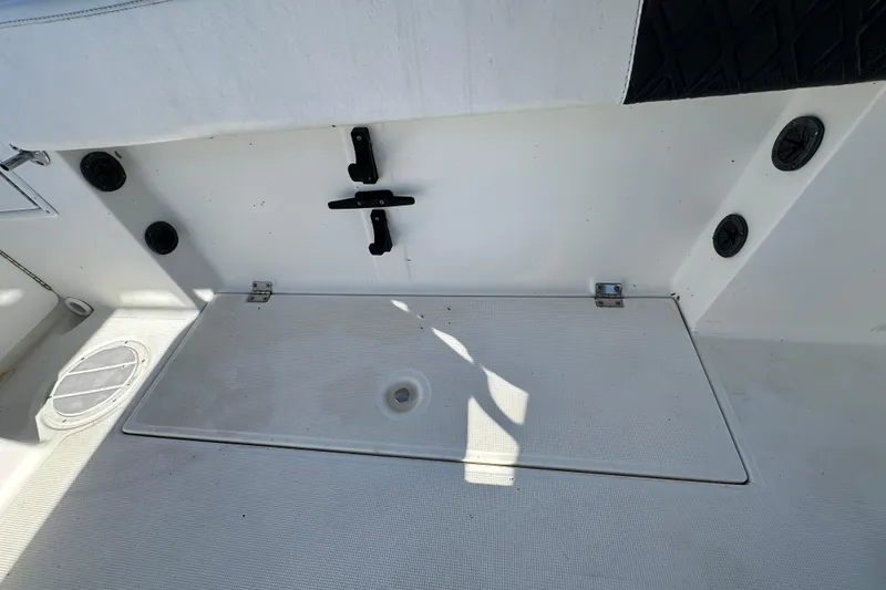 Slide: The Image of 1999 Robalo 2420 Center Console boat deck with storage compartment and rod holders. - 54