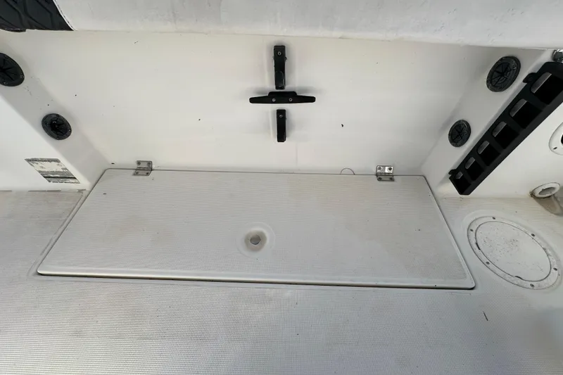 Slide: The Image of 1999 Robalo 2420 Center Console boat deck with storage compartment and rod holders. - 57