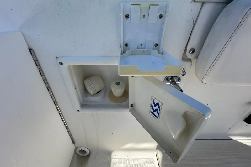 Slide: The Image of 1999 Robalo 2420 Center Console boat compartment with open hatch and storage items. - 61