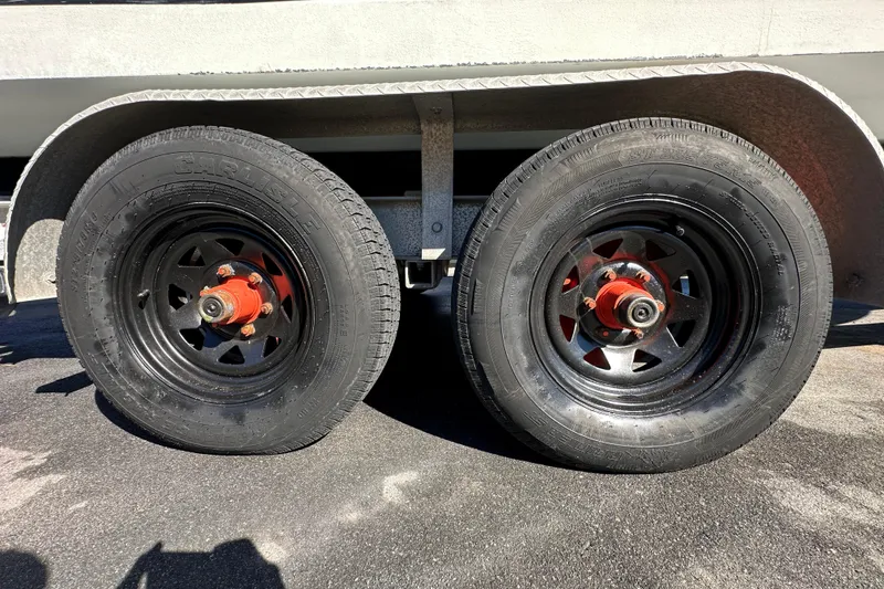 Slide: The Image of Trailer wheels of a 1999 Robalo 2420 Center Console boat on asphalt. - 80