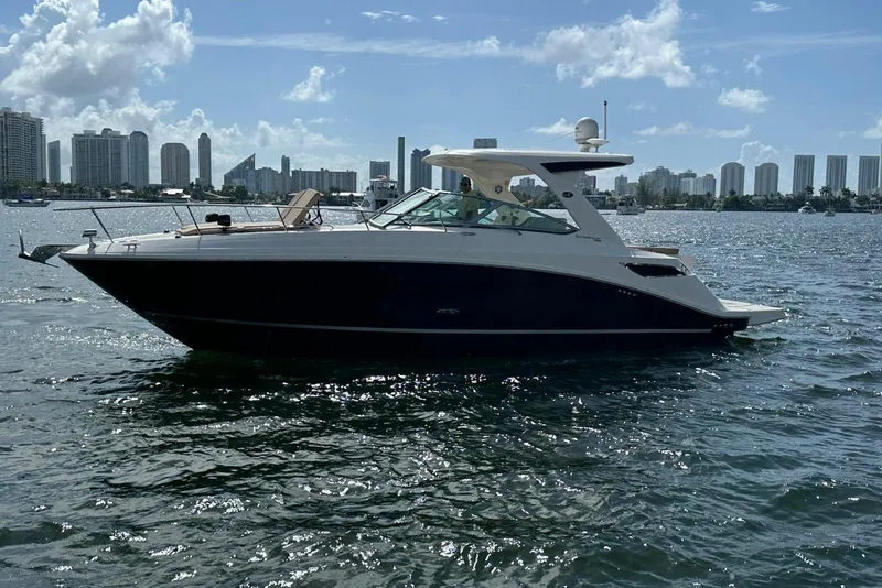 The Image of 2016 Sea Ray 350 Sundancer yacht cruising on a sunny day with city skyline backdrop. - 0