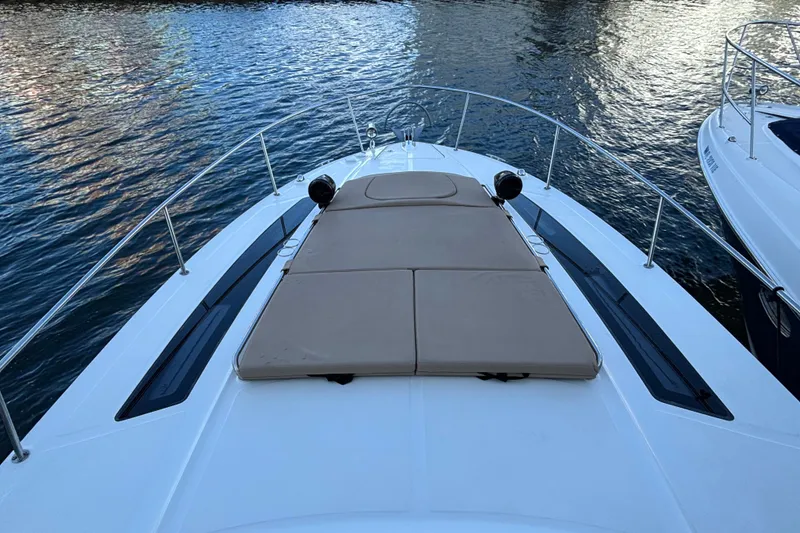 Slide: The Image of 2016 Sea Ray 350 Sundancer boat with sunpad on deck, docked on calm water. - 21