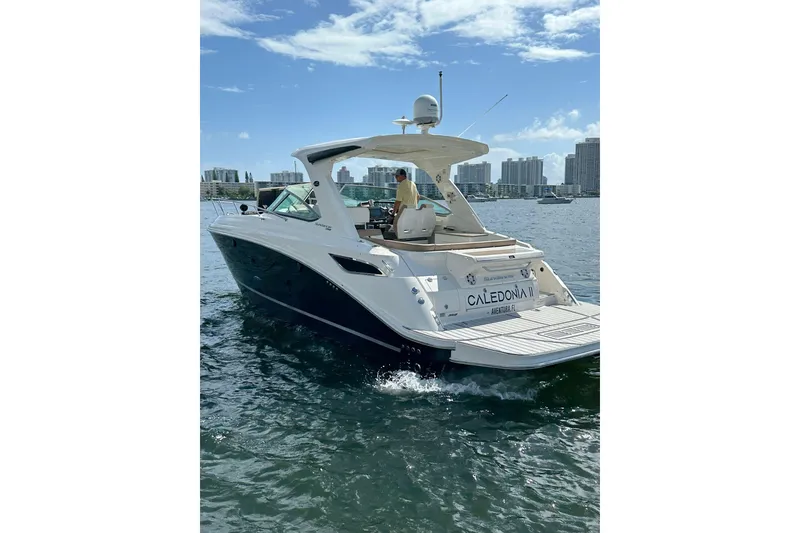 Slide: The Image of 2016 Sea Ray 350 Sundancer yacht cruising on a sunny day with city skyline backdrop. - 3