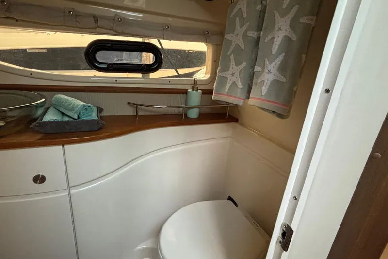 Slide: The Image of 2016 Sea Ray 350 Sundancer bathroom with starfish curtains and wooden countertop. - 37