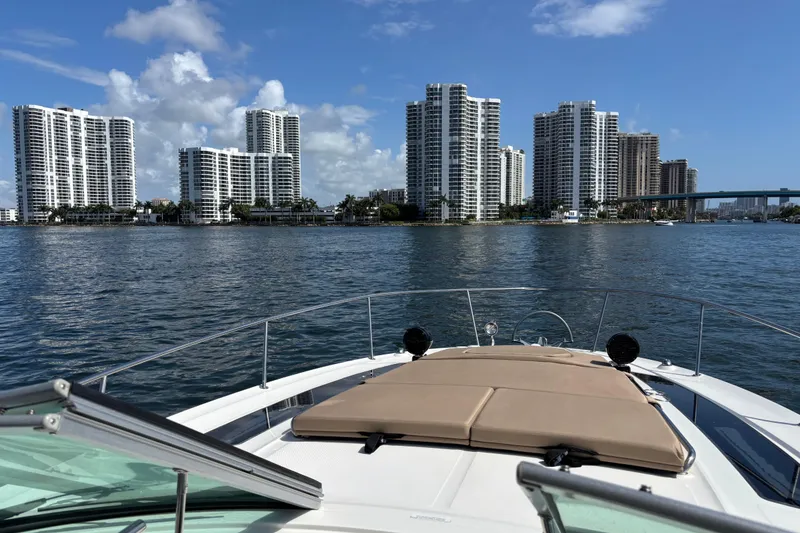 Slide: The Image of 2016 Sea Ray 350 Sundancer cruising near waterfront skyscrapers under a clear blue sky. - 40