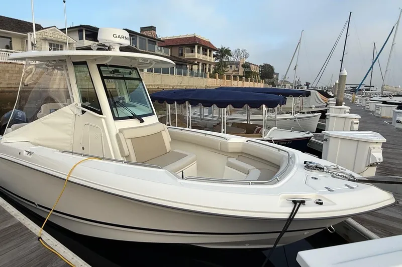 Slide: The Image of 2025 Boston Whaler 250 Outrage docked at marina, showcasing sleek design and spacious seating. - 10