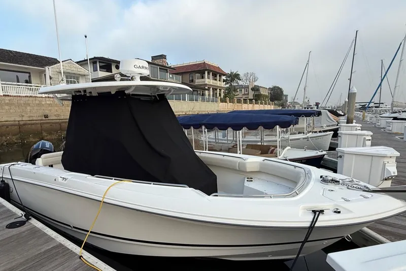Slide: The Image of 2025 Boston Whaler 250 Outrage boat docked at marina with cover. - 14