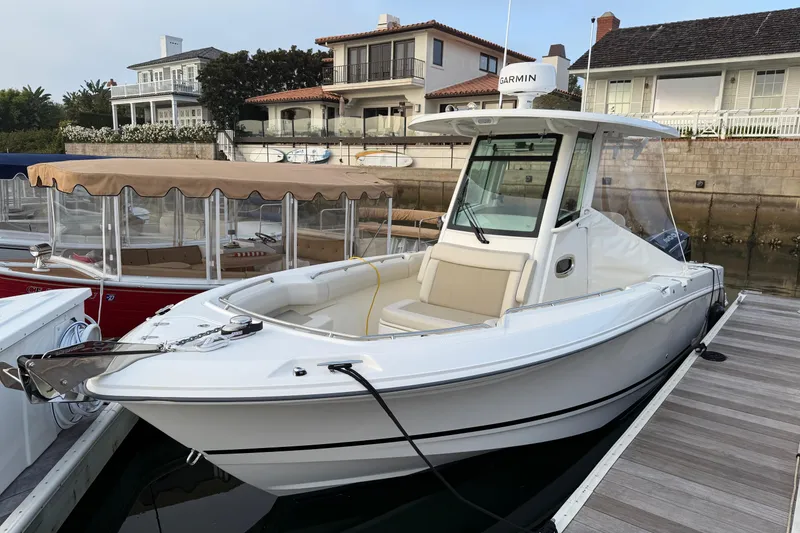 Slide: The Image of 2025 Boston Whaler 250 Outrage boat on calm water, featuring Mercury engines. - 2