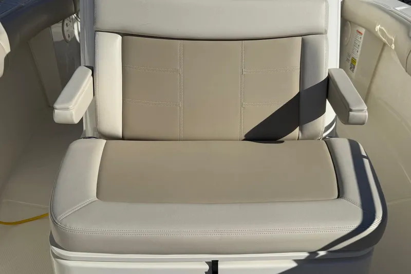 Slide: The Image of 2025 Boston Whaler 250 Outrage seat with storage compartment, featuring beige upholstery. - 38