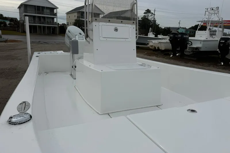 Slide: The Image of 2026 Lookout Bay 19 boat with white deck and console, parked near other boats. - 14