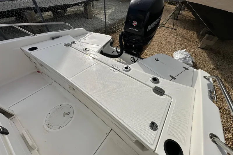 Slide: The Image of 2016 Boston Whaler 210 Dauntless boat deck with Mercury engine, parked on gravel. - 3