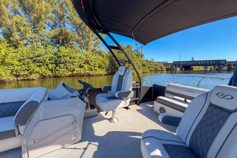 Slide: The Image of 2023 Harris Sunliner 230 Sport pontoon boat on a scenic river with lush greenery. - 16