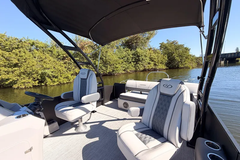 Slide: The Image of 2023 Harris Sunliner 230 Sport boat interior with luxury seating on a calm river. - 17