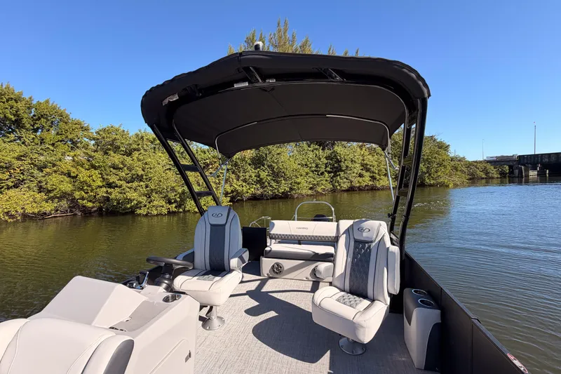 Slide: The Image of 2023 Harris Sunliner 230 Sport pontoon boat on a serene river with lush greenery. - 18