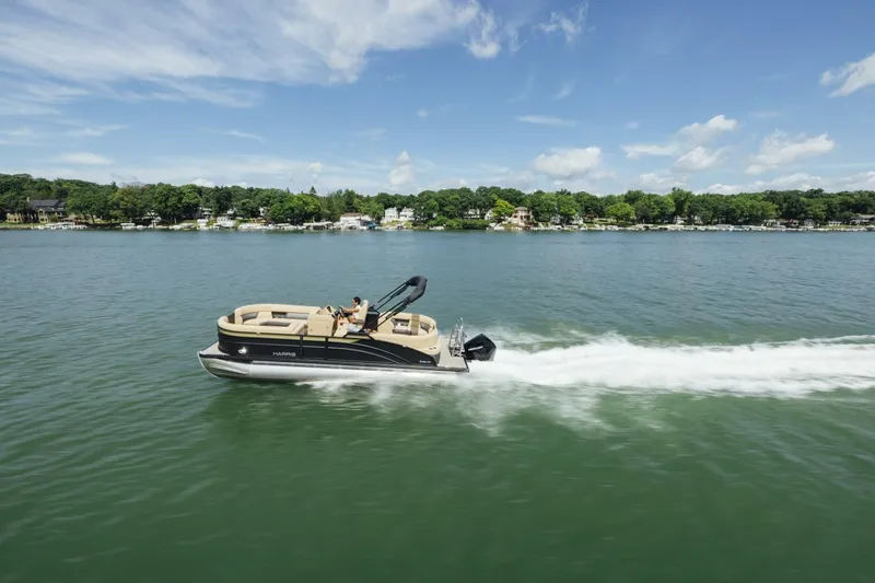 Slide: The Image of 2023 Harris Sunliner 230 Sport pontoon boat on water, surrounded by palm trees and RVs. - 2