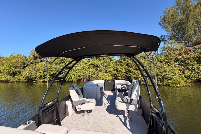 Slide: The Image of 2023 Harris Sunliner 230 Sport pontoon boat on a serene lake. - 20