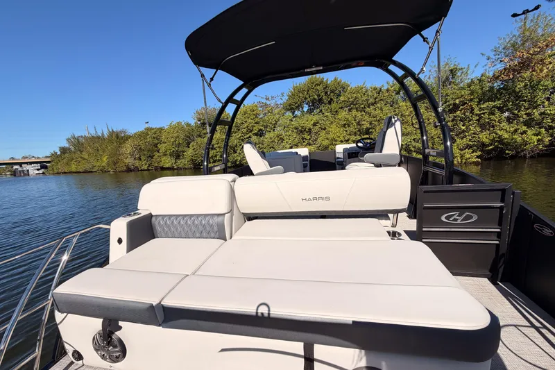 Slide: The Image of 2023 Harris Sunliner 230 Sport pontoon boat with sleek seating and canopy on a serene lake. - 22