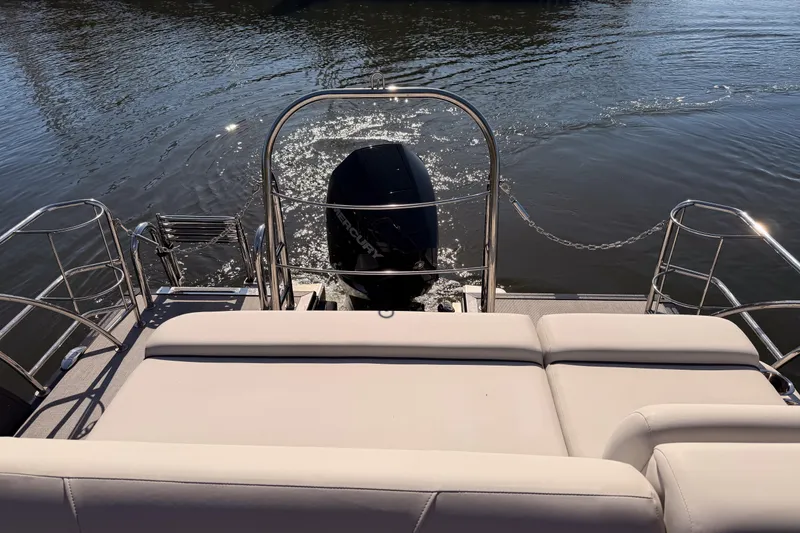 Slide: The Image of 2023 Harris Sunliner 230 Sport boat with rear seating and outboard motor on water. - 23