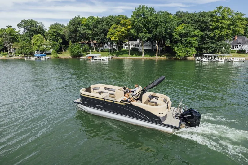 Slide: The Image of 2023 Harris Sunliner 230 Sport pontoon boat on water, with palm trees in background. - 3