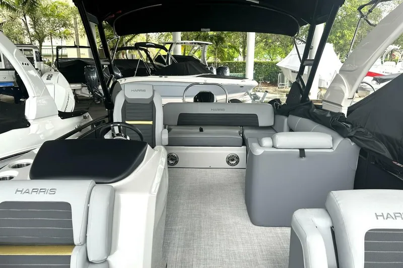 Slide: The Image of 2023 Harris Sunliner 250 Sport boat interior with covered seating and helm chairs. - 6