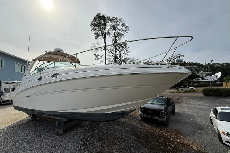 The Image of 2001 Sea Ray 280 Sundancer boat on display, parked on gravel near vehicles. - 0