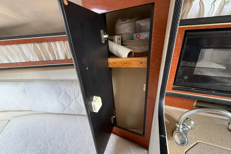 Slide: The Image of Interior of 2001 Sea Ray 280 Sundancer with open cabinet and kitchen amenities. - 12