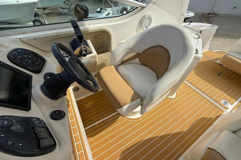 Slide: The Image of 2001 Sea Ray 280 Sundancer helm with steering wheel and beige seating. - 8