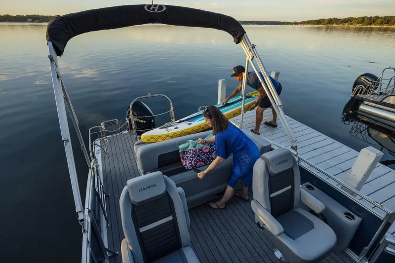 Slide: The Image of 2023 Harris Solstice 250 pontoon boat docked, with people loading items onboard. - 8
