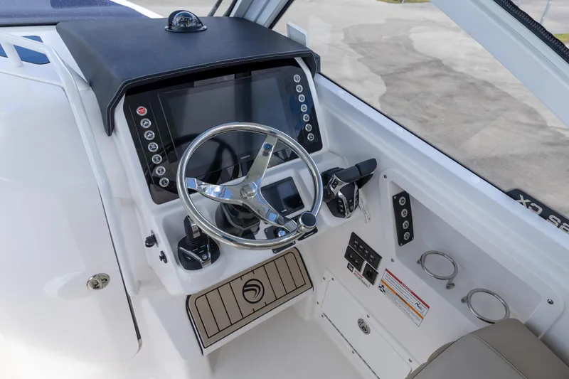 Slide: The Image of 2026 Edgewater 262CX Crossover boat helm with modern controls and steering wheel. - 2