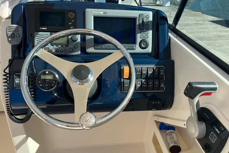 Slide: The Image of 2012 Pursuit DC 265 Dual Console boat dashboard with steering wheel and control panel. - 4
