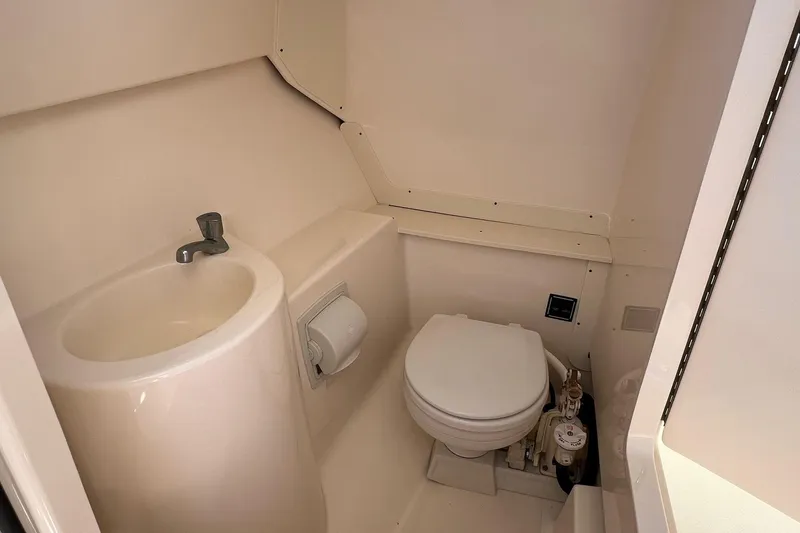 Slide: The Image of Compact bathroom in 2012 Pursuit DC 265 Dual Console boat, featuring sink and toilet. - 5