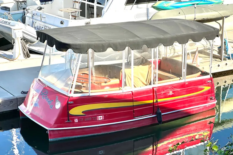 Slide: The Image of Red 2006 Duffy Cat 16 electric boat docked, featuring a black canopy and clear side panels. - 18