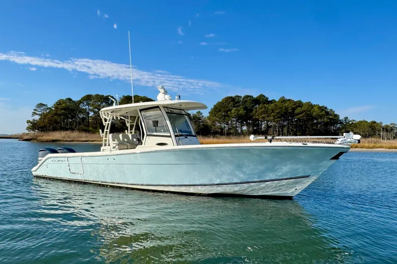 The Image of 2015 Cobia 344 Center Console boat on calm water with trees in the background. - 0