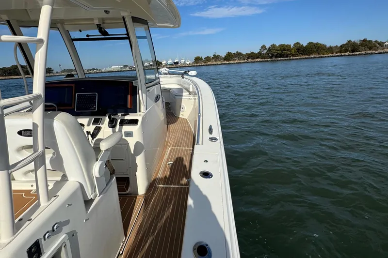 Slide: The Image of 2015 Cobia 344 Center Console boat on calm water, featuring a sleek deck design. - 11