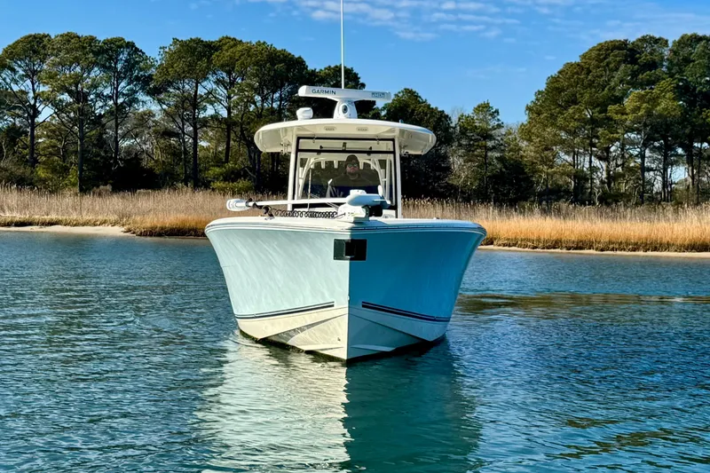 Slide: The Image of 2015 Cobia 344 Center Console boat on calm water, surrounded by trees. - 2