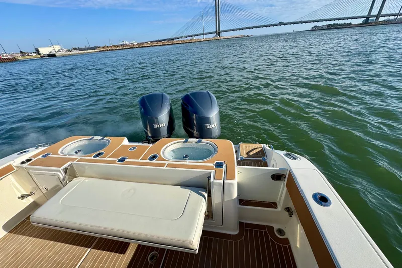 Slide: The Image of 2015 Cobia 344 Center Console boat with twin 300 engines on water, bridge in background. - 20