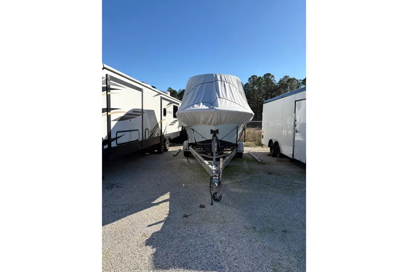 Slide: The Image of 2016 Sea Fox 249 Avenger boat covered and parked between trailers. - 12