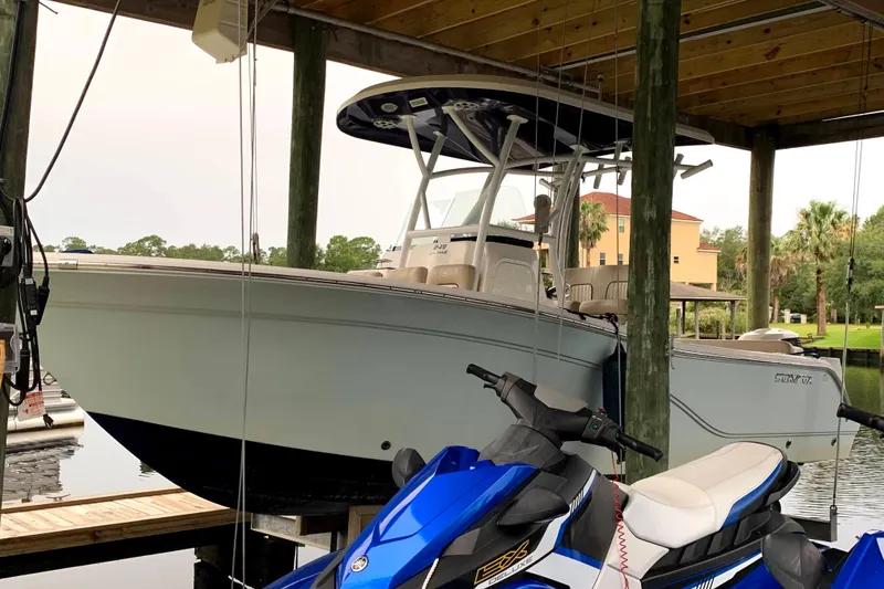 Slide: The Image of 2016 Sea Fox 249 Avenger boat docked under shelter with jet ski nearby. - 2
