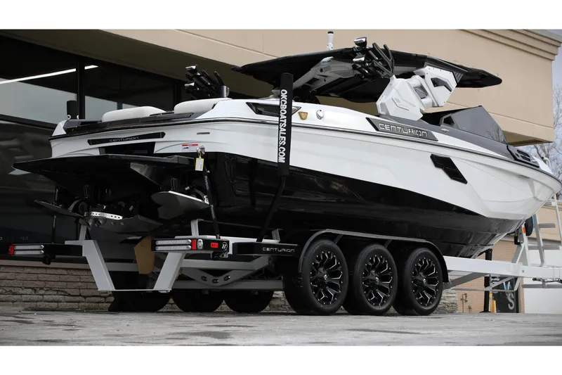 Slide: The Image of 2026 Centurion Ri245 boat on trailer, sleek black and white design, parked outdoors. - 23