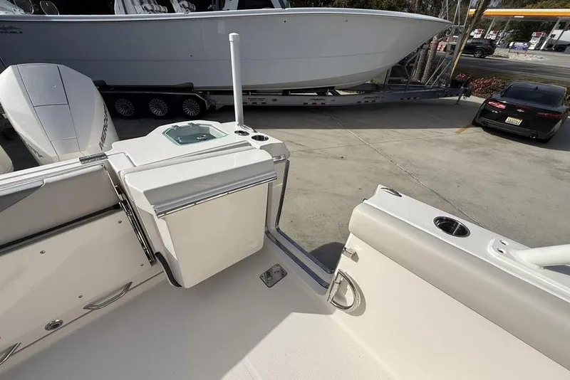 Slide: The Image of 2026 Sailfish 276 DC boat interior with seating and storage, parked near a trailer and car. - 13