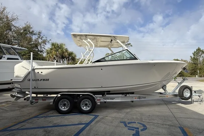 Slide: The Image of 2026 Sailfish 276 DC boat on trailer, parked outdoors under cloudy sky. - 6
