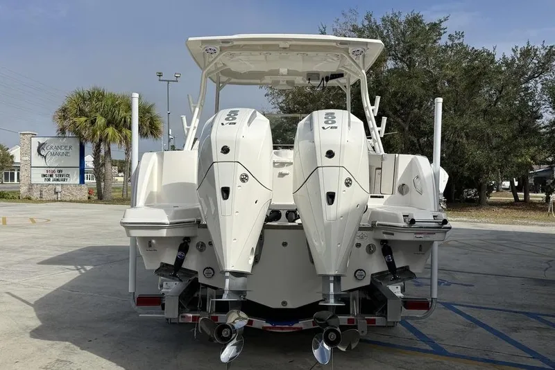 Slide: The Image of 2026 Sailfish 276 DC boat with dual outboard engines, parked outdoors near palm trees. - 9