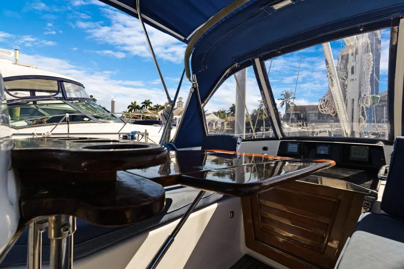 Slide: The Image of 2009 Hylas 46 yacht cockpit with blue canopy, marina view, and polished wood table. - 20