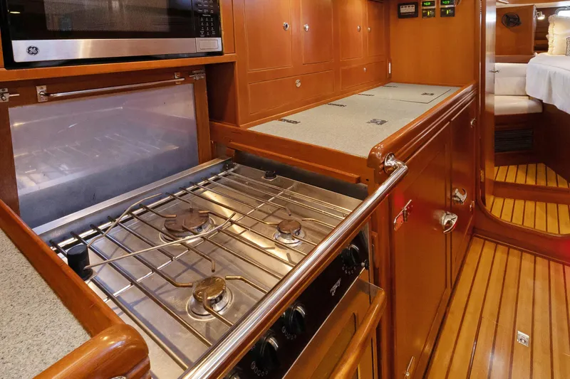 Slide: The Image of 2009 Hylas 46 yacht interior kitchen with stove, microwave, and wooden cabinetry. - 35