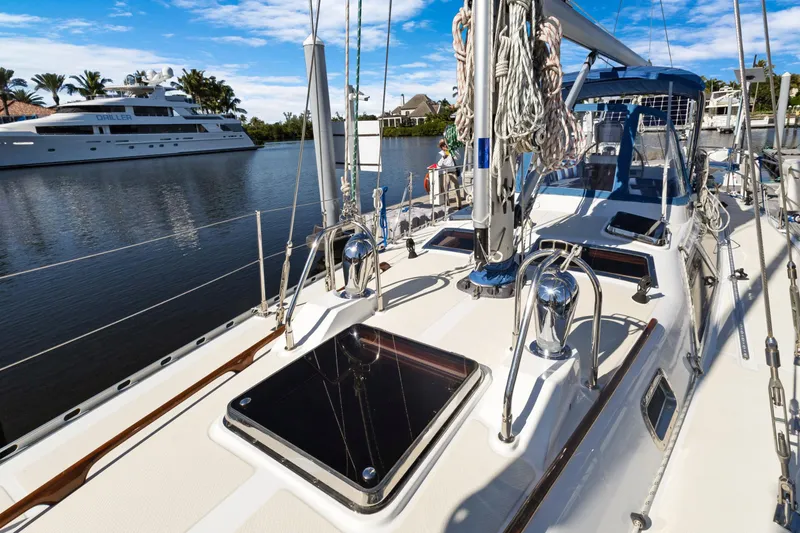 Slide: The Image of 2009 Hylas 46 sailboat deck with marina view, featuring clear skies and luxury yacht nearby. - 4