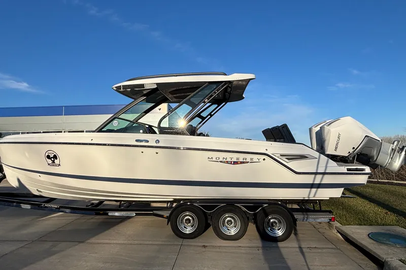 The Image of 2026 Monterey Elite 30 OB boat on trailer, side view under clear blue sky. - 1