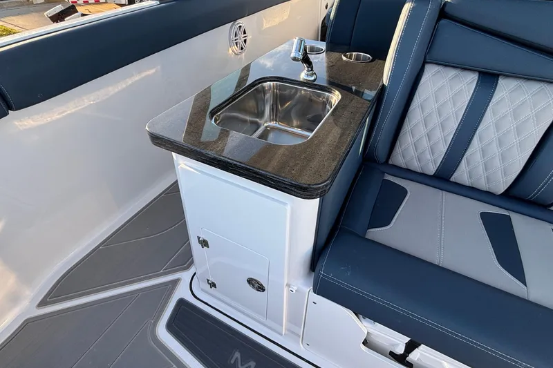 Slide: The Image of 2026 Monterey Elite 30 OB boat interior with sink and cushioned seating. - 13